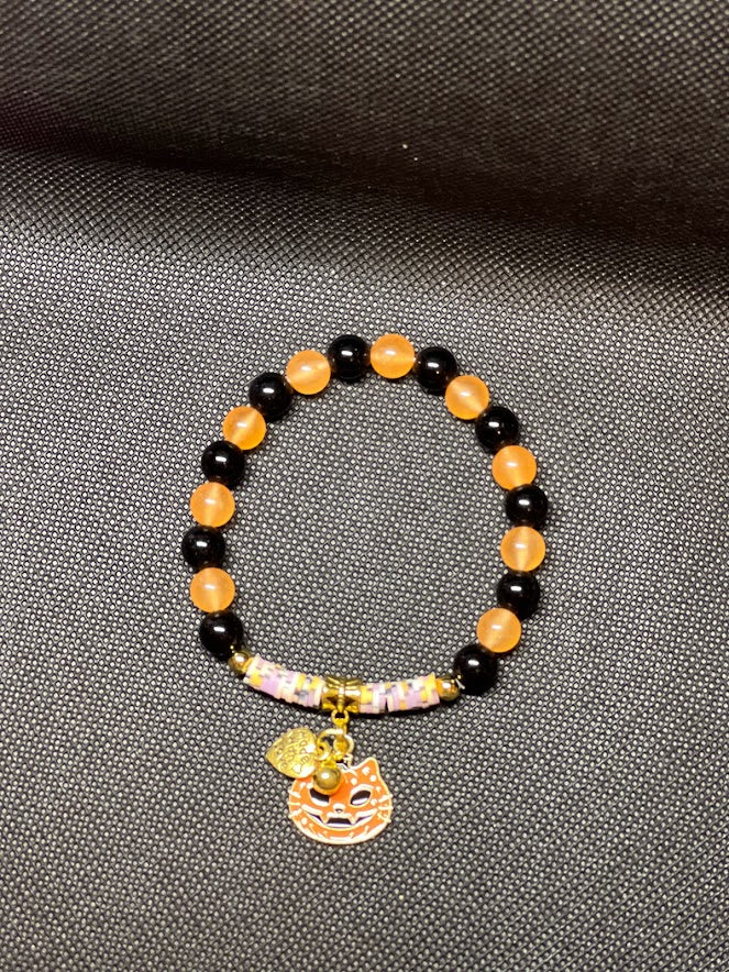 Black Onyx beads and orange (dyed) beads with gold toned spacers and charms.